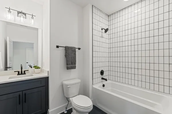 a bathroom with a bathtub shower sink mirror vanity and toilet