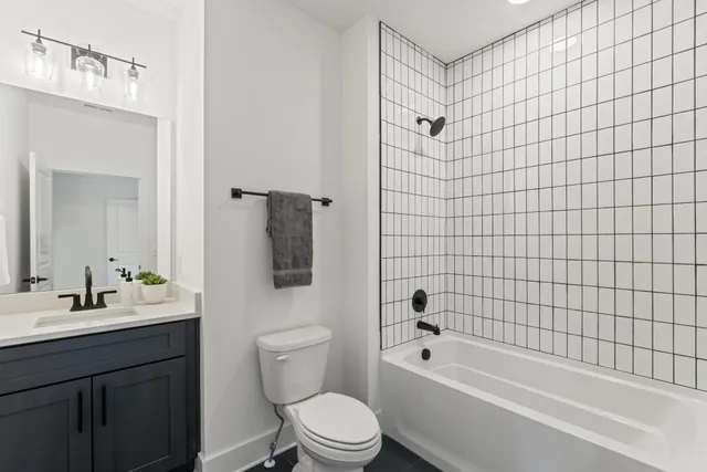 a bathroom with a bathtub shower sink mirror vanity and toilet
