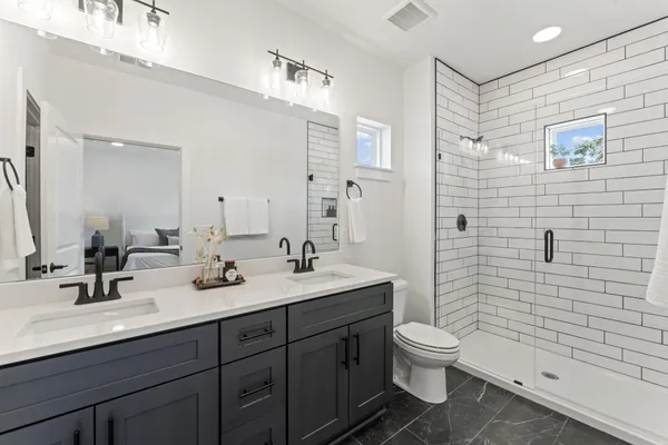 a bathroom with a double vanity sink toilet and shower