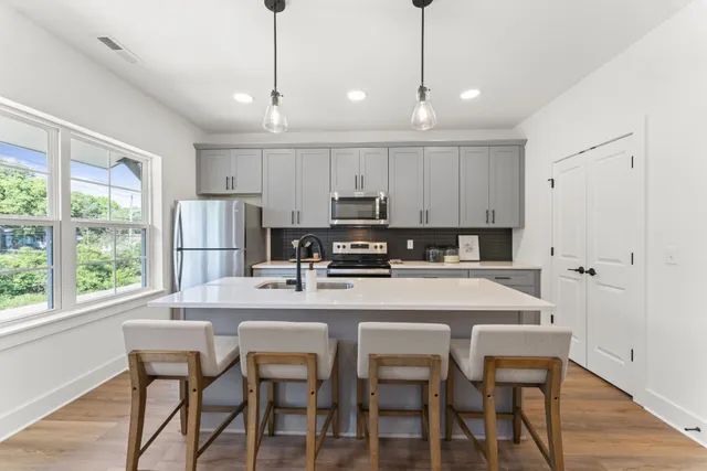 a kitchen with stainless steel appliances granite countertop a dining table chairs refrigerator and cabinets