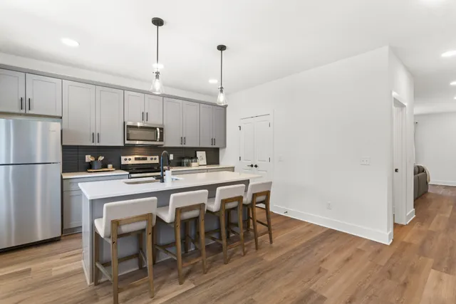 a kitchen with stainless steel appliances granite countertop a white table and chairs