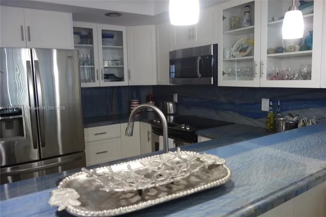 a kitchen with stainless steel appliances wooden floor and a refrigerator