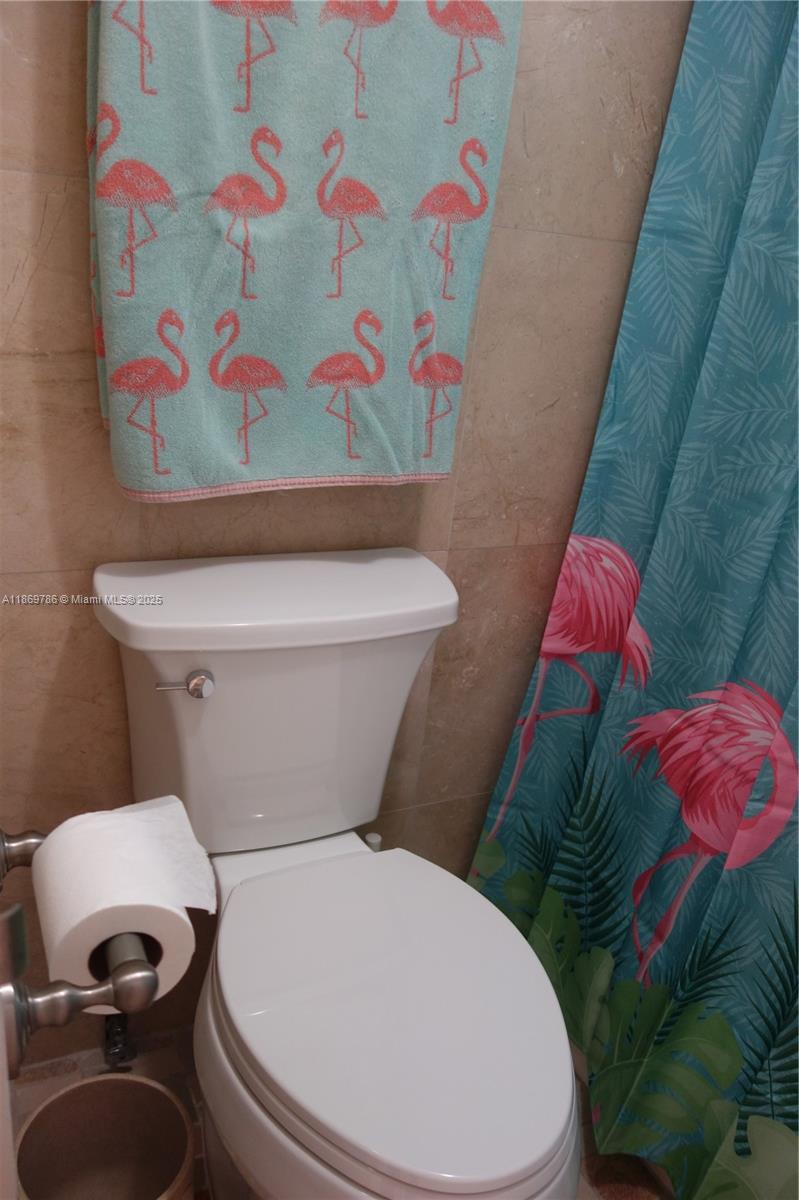5701 Collins Avenue, Unit 1510 Miami Beach, FL 33140 - Photo 28 of 67 a white toilet sitting next to a shower curtain