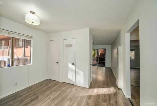 a view of an empty room with wooden floor and a window