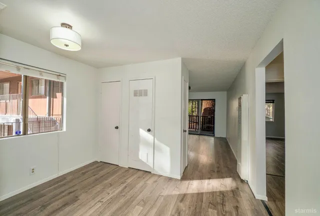 a view of an empty room with a window and wooden floor