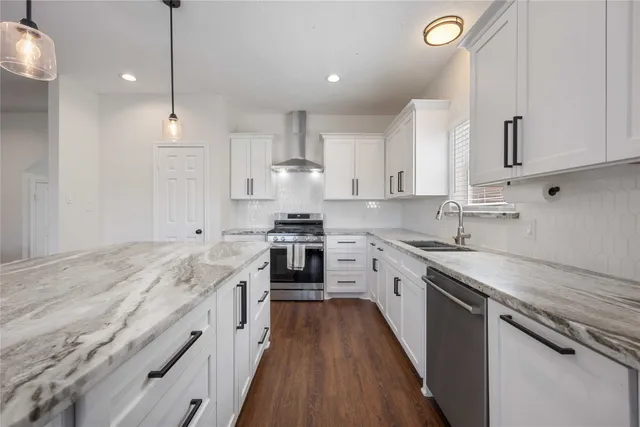 a kitchen with granite countertop a sink a counter space stainless steel appliances and cabinets
