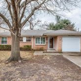 a front view of a house with a garden and trees