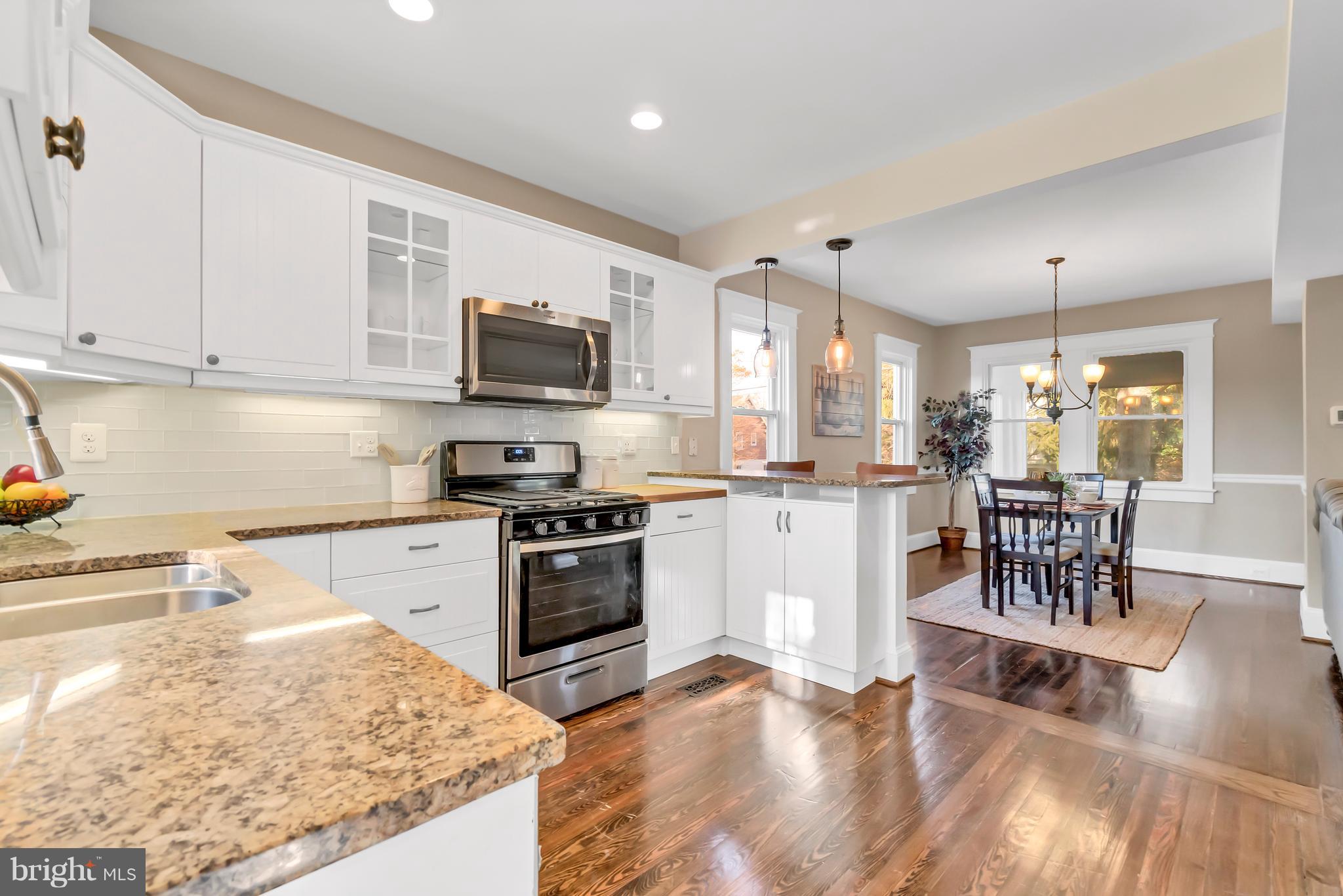 605 St Dunstans Road Baltimore, MD 21212 - Photo 14 of 43 a kitchen with stainless steel appliances granite countertop a stove top oven a sink a dining table and chairs with wooden floor