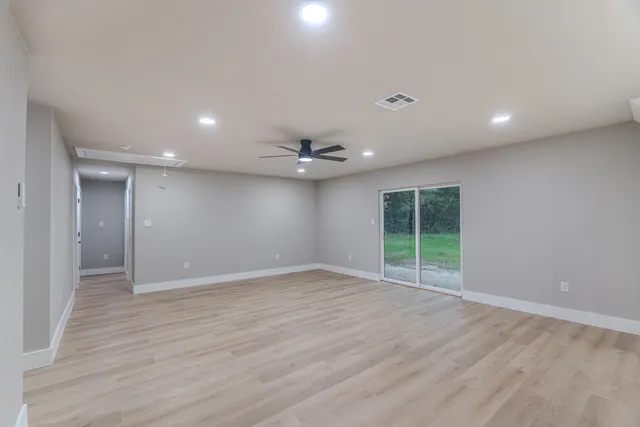 an empty room with wooden floor and a ceiling fan