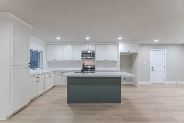 a large kitchen with stainless steel appliances a large counter top a stove and a refrigerator