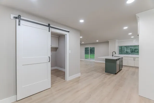 a view of kitchen with stainless steel appliances wooden floor and window