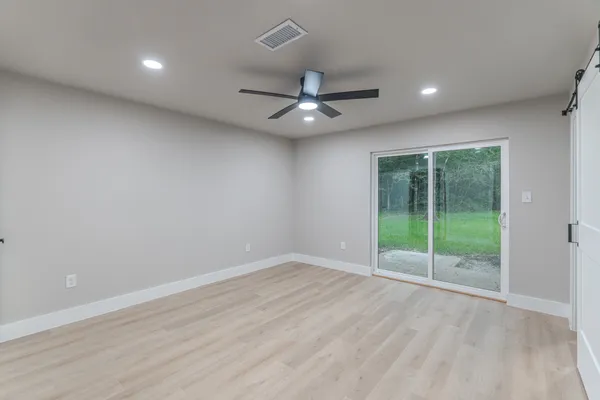an empty room with floor to ceiling fan and windows