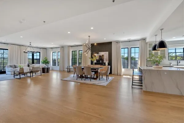 a kitchen with stainless steel appliances a stove a sink a oven a dining table and chairs with wooden floor