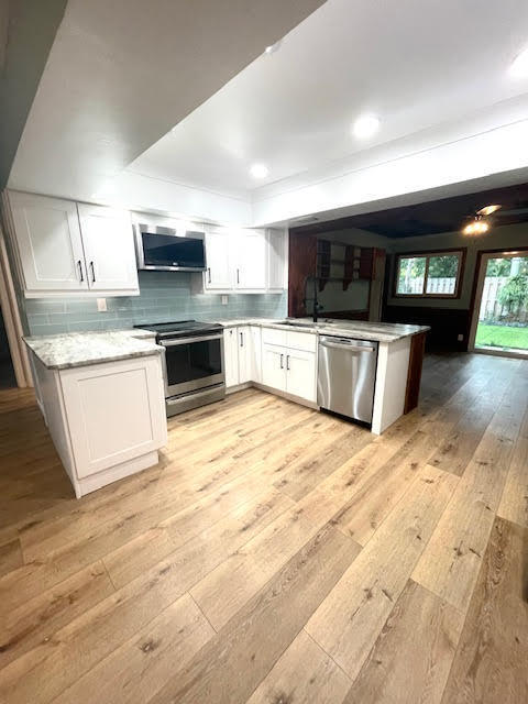 200 Lancaster Street Boca Raton, FL 33487 - Photo 9 of 43 a kitchen with stainless steel appliances kitchen island granite countertop a stove top oven a sink dishwasher a dining table and chairs with wooden floor