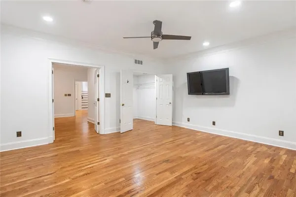 a view of empty room with wooden floor and fan