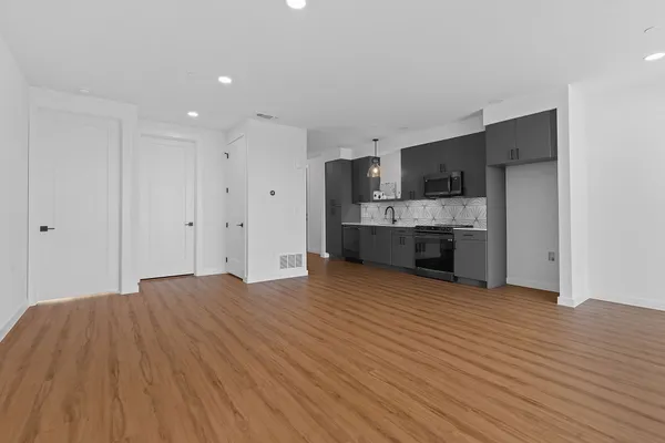 a view of kitchen and empty room with wooden floor