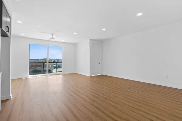 a view of an empty room with wooden floor and a window