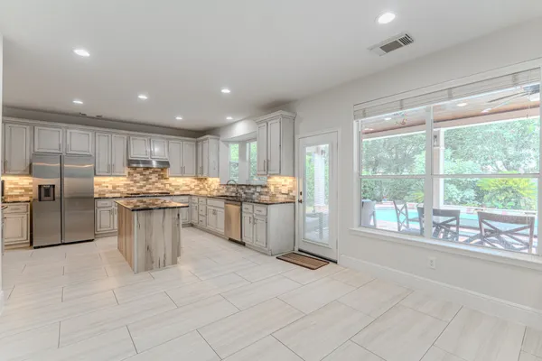 a kitchen with stainless steel appliances granite countertop a stove top oven a sink dishwasher and a refrigerator