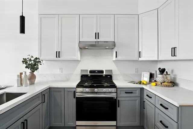 a kitchen with stainless steel appliances granite countertop white cabinets a stove a sink and dishwasher
