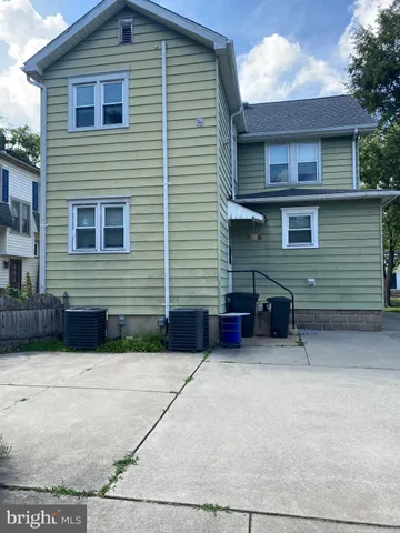 a view of a house with a small yard and a large tree