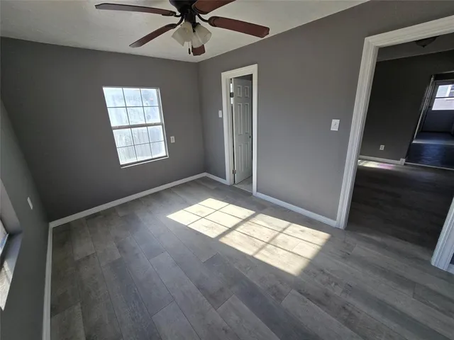 a view of empty room with wooden floor and fan