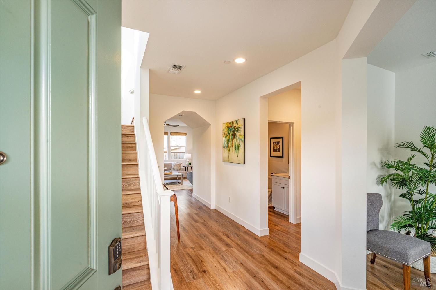 a view of a hallway with wooden floor and a living room