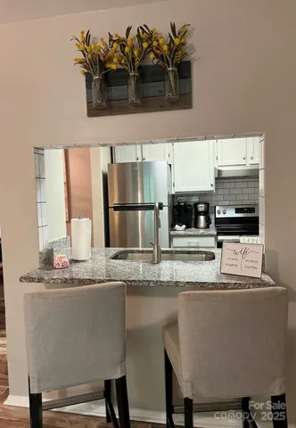 a view of kitchen with stainless steel appliances granite countertop a sink and cabinets