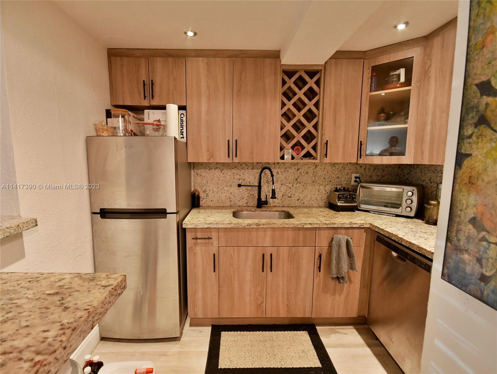 8609 Southwest 68th Court, Unit 5 Pinecrest, FL 33156 - Photo 12 of 27 a kitchen with a refrigerator a sink and wooden cabinets