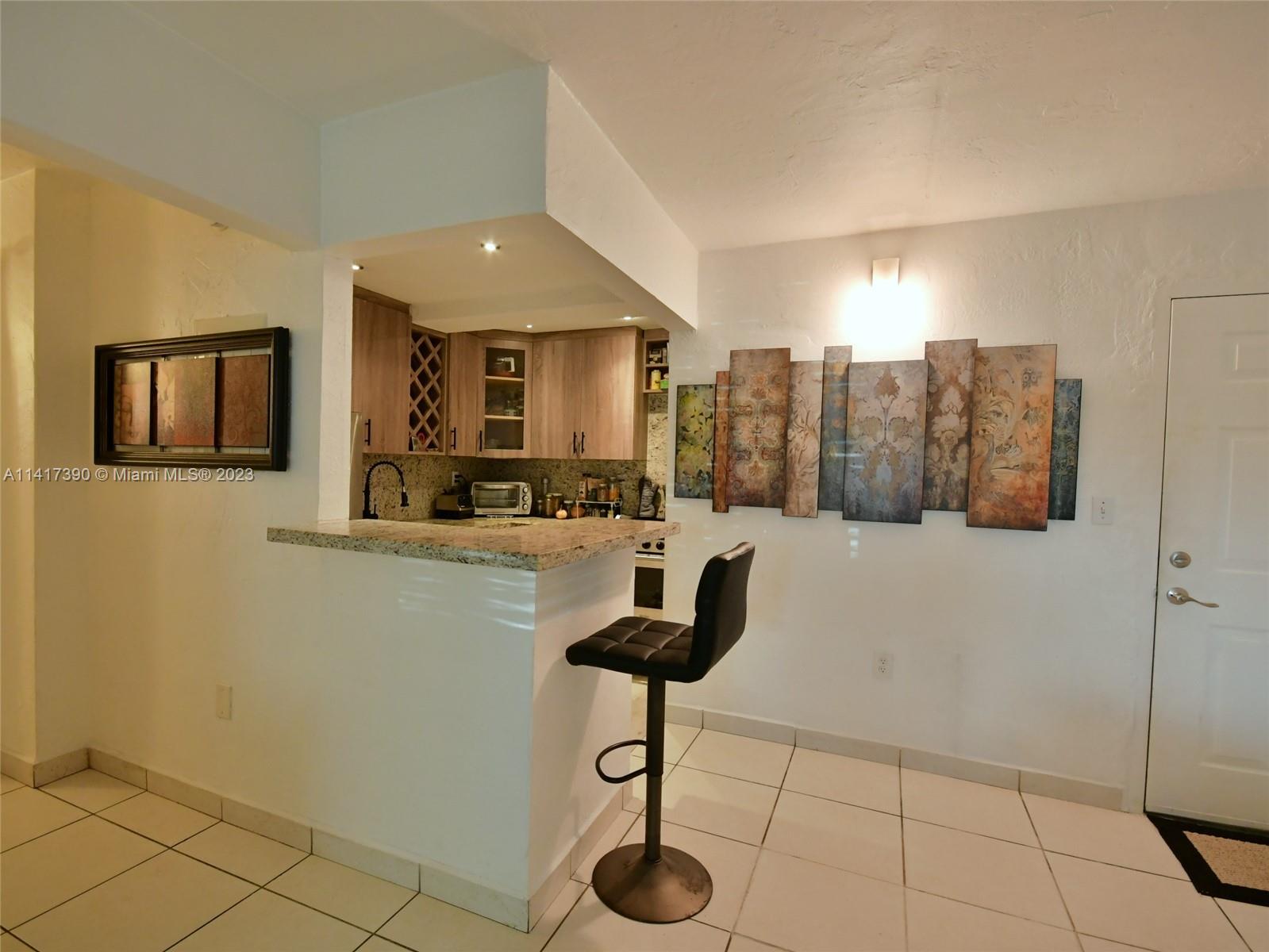 8609 Southwest 68th Court, Unit 5 Pinecrest, FL 33156 - Photo 9 of 27 a kitchen with granite countertop a coffee maker a refrigerator and cabinets