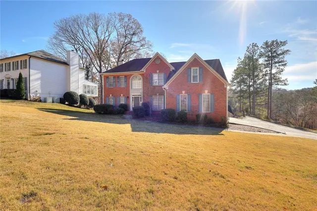 a front view of a house with a yard covered with snow and trees