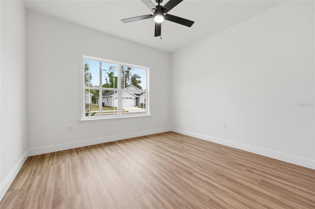 6735 Southwest 10th Lane Gainesville, FL 32607 - Photo 14 of 24 an empty room with wooden floor chandelier fan and windows