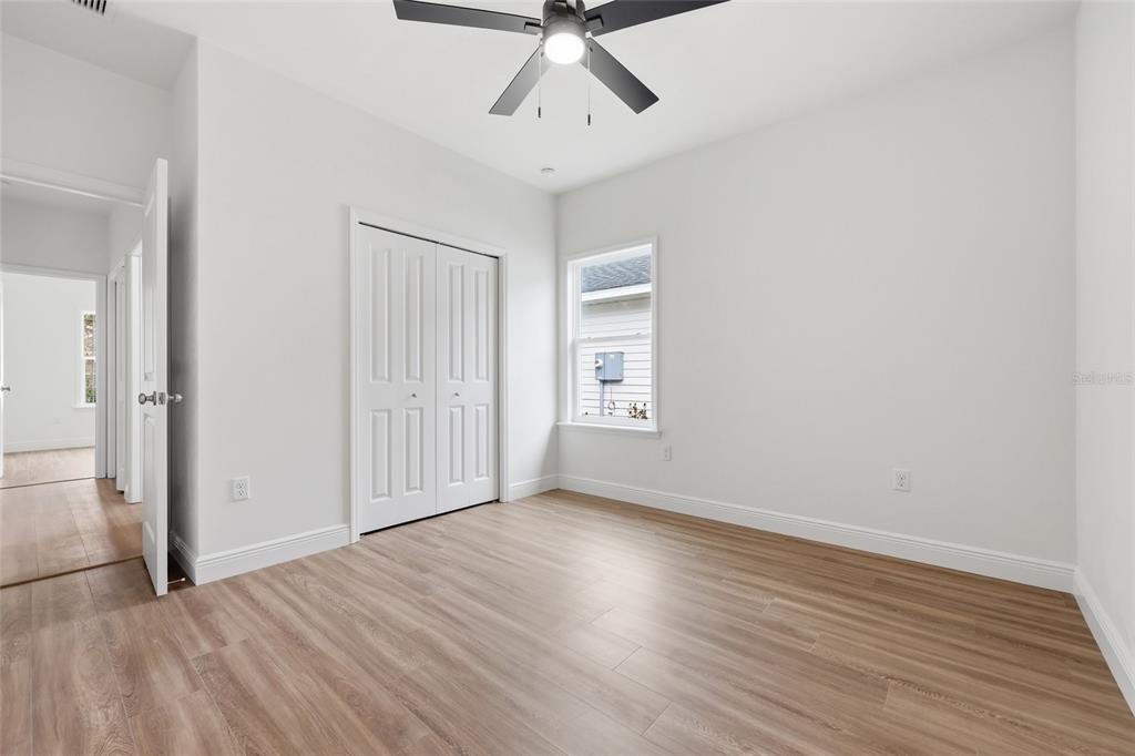 6735 Southwest 10th Lane Gainesville, FL 32607 - Photo 16 of 24 an empty room with wooden floor chandelier fan and windows