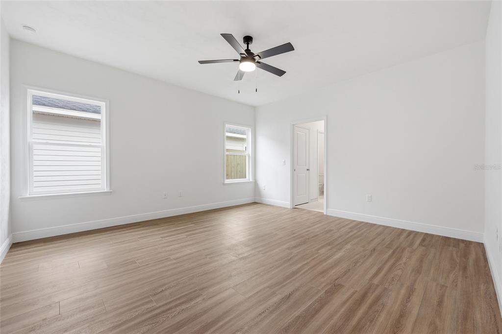 6735 Southwest 10th Lane Gainesville, FL 32607 - Photo 10 of 24 an empty room with wooden floor fan and windows