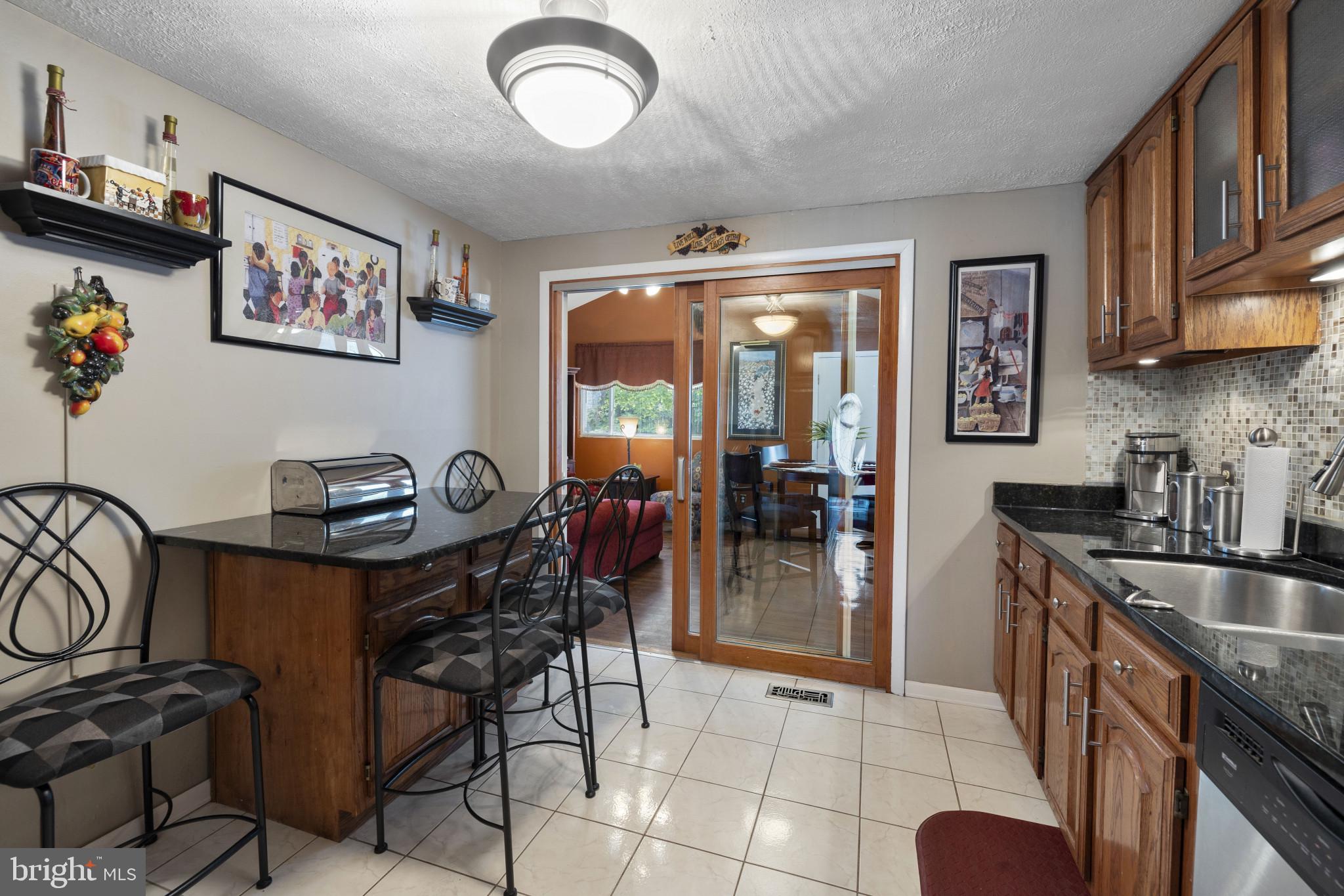 4105 Hanwell Road Randallstown, MD 21133 - Photo 17 of 37 a kitchen with stainless steel appliances granite countertop a stove a refrigerator a sink a dining table and chairs with the wooden floor