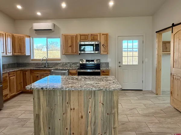 a kitchen with kitchen island granite countertop a stove and a sink
