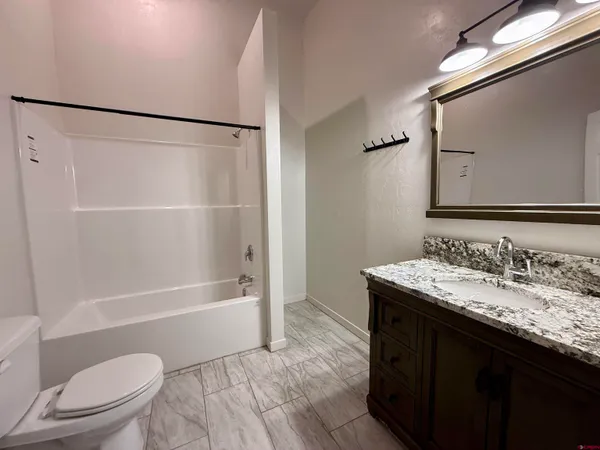 a bathroom with a granite countertop toilet sink and mirror