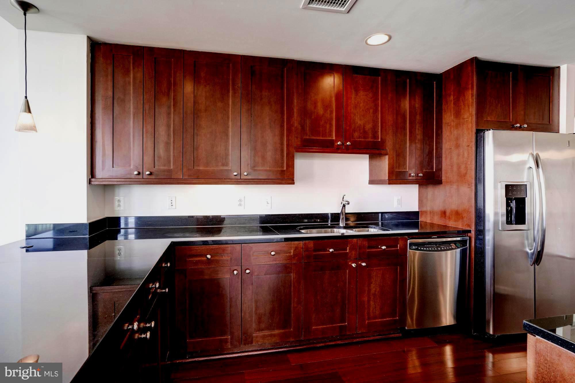 11990 Market Street, Unit 713 Reston, VA 20190 - Photo 14 of 30 a kitchen with wooden cabinets and stainless steel appliances