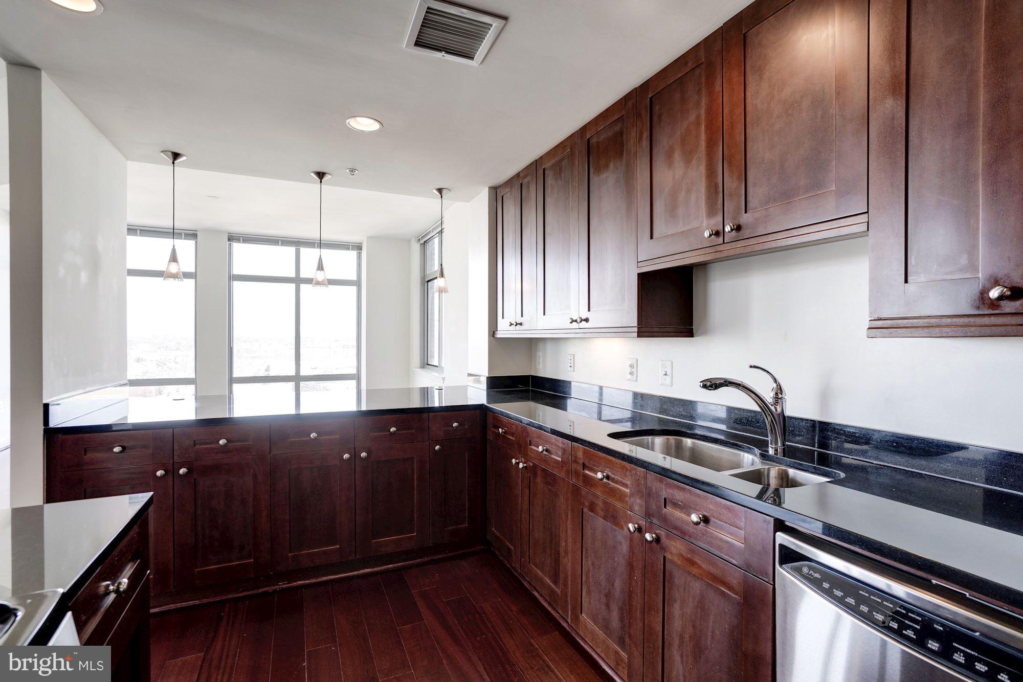 11990 Market Street, Unit 713 Reston, VA 20190 - Photo 15 of 30 a kitchen with granite countertop wooden cabinets a sink and dishwasher
