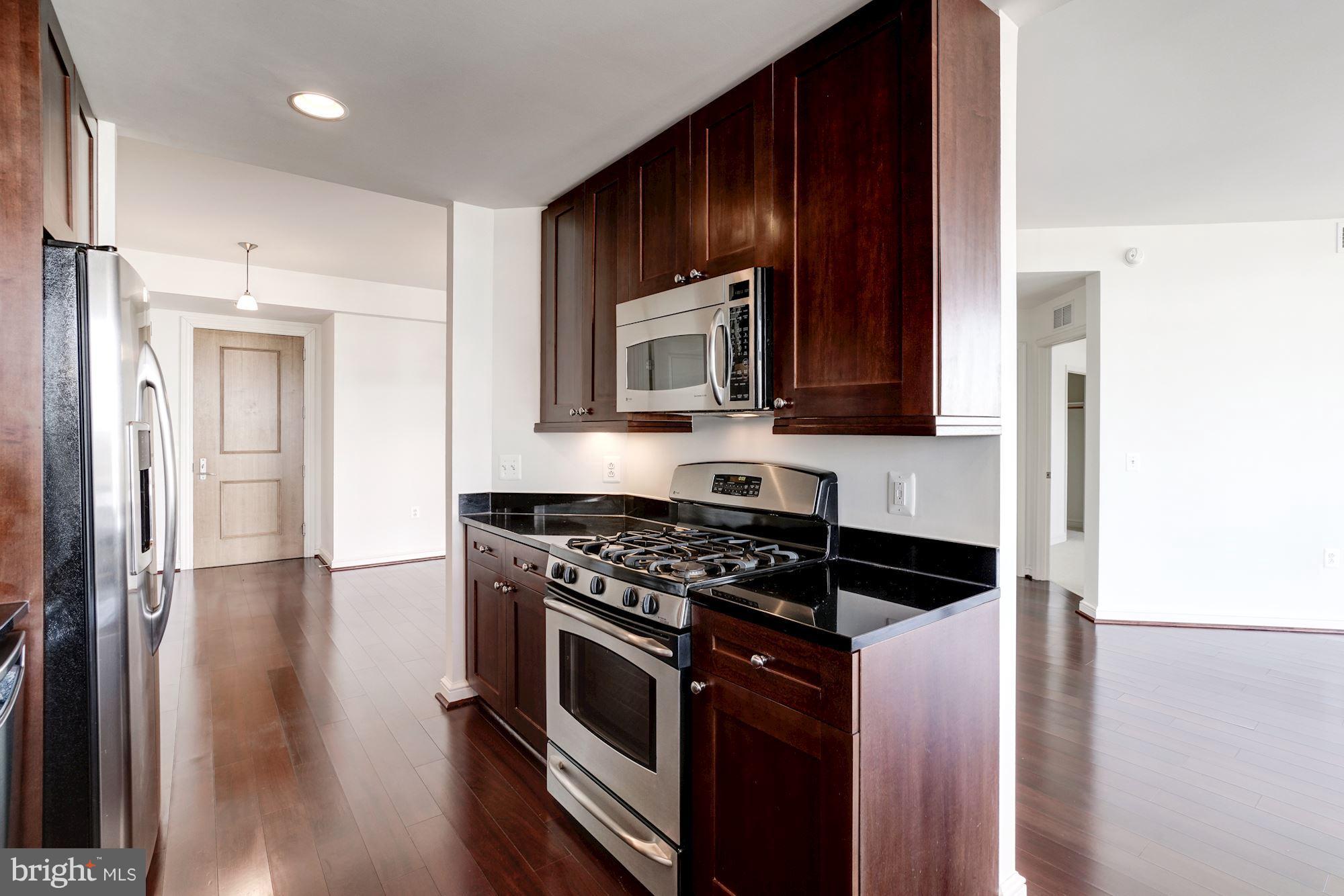 11990 Market Street, Unit 713 Reston, VA 20190 - Photo 16 of 30 a kitchen with granite countertop a stove and a microwave