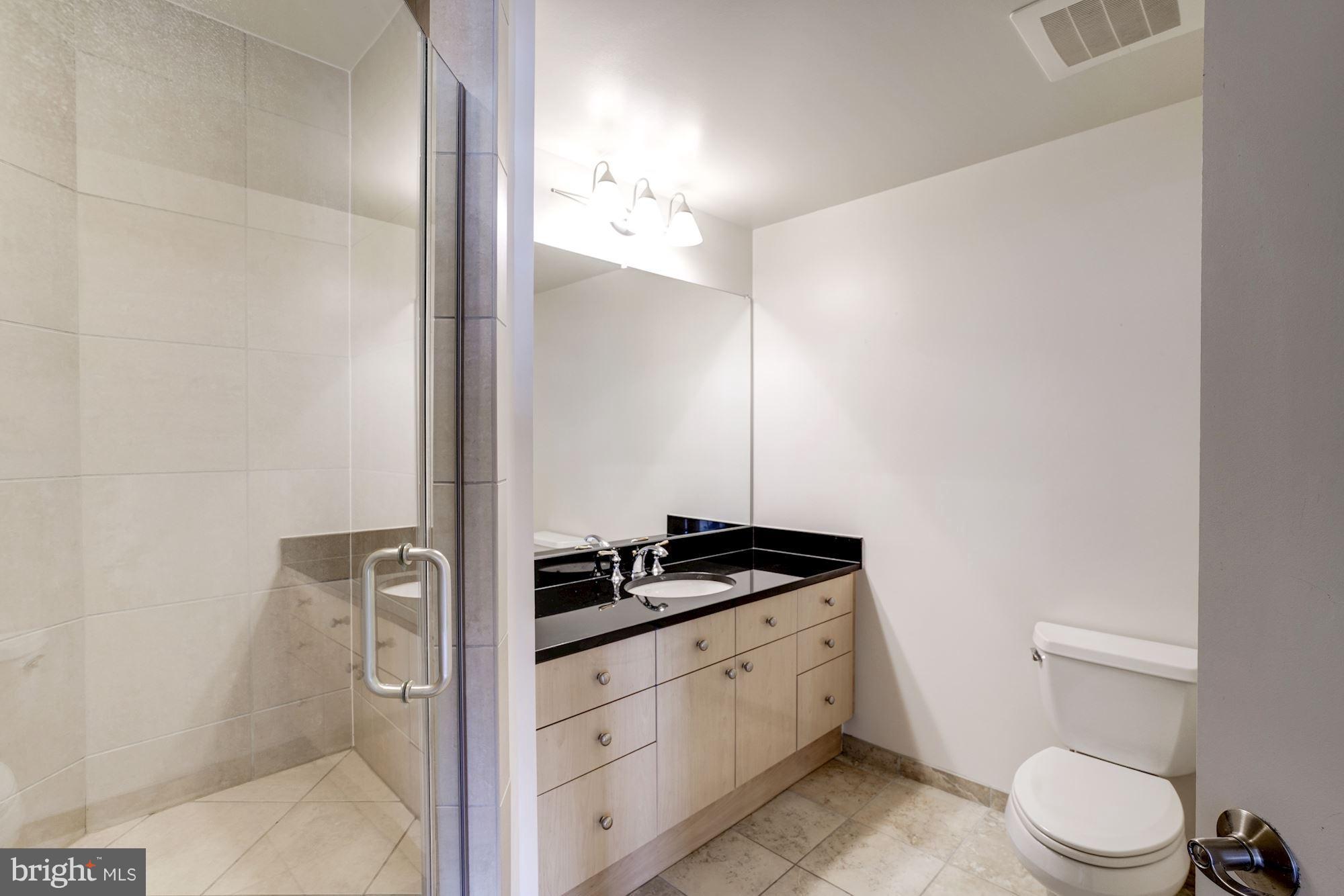 11990 Market Street, Unit 713 Reston, VA 20190 - Photo 22 of 30 a bathroom with a granite countertop sink a toilet a mirror and vanity