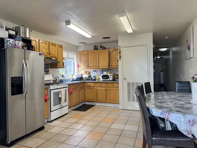 a living room with patio furniture and a dining table with kitchen view