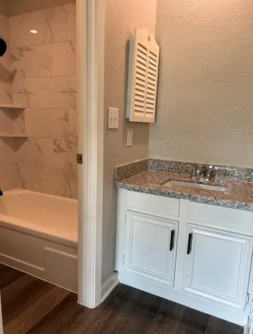 a bathroom with a granite countertop sink and tub