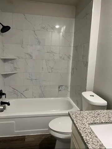 a bathroom with a granite countertop toilet a sink and bathtub