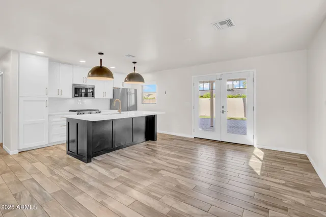 a kitchen with stainless steel appliances granite countertop a sink cabinets and wooden floor