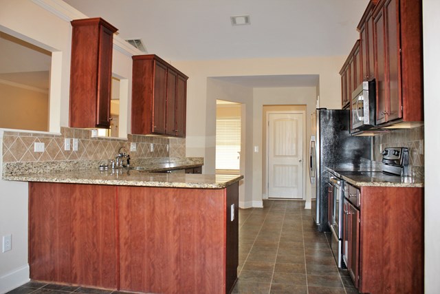 2141 Lee Road Phenix City, AL 36870 - Photo 12 of 24 a large kitchen with granite countertop a sink refrigerator and cabinets