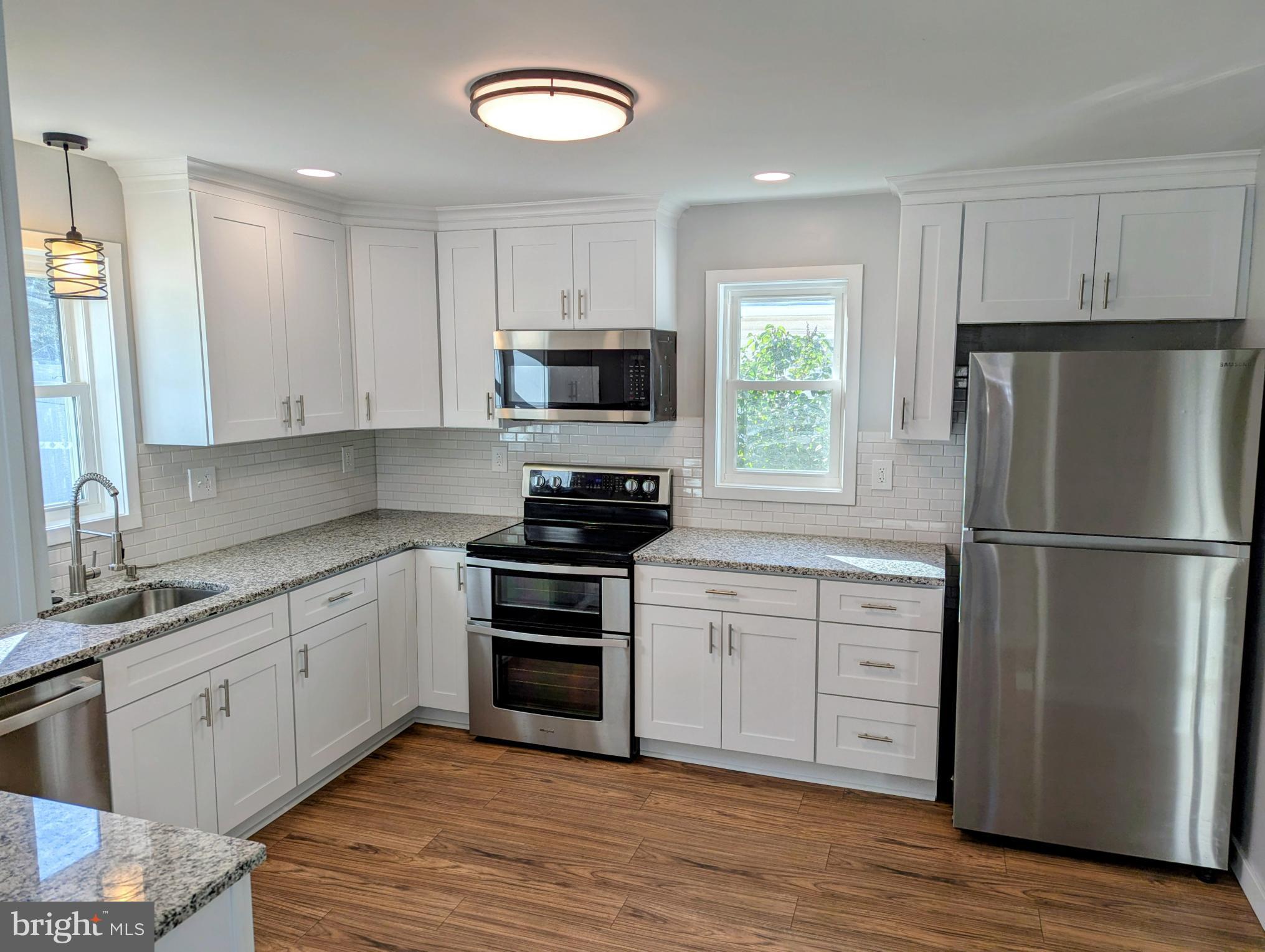 4917 Shepherd Street Brookhaven, PA 19015 - Photo 8 of 34 a kitchen with white cabinets white stainless steel appliances and wooden floors