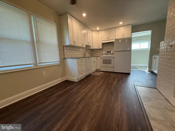 a kitchen with stainless steel appliances granite countertop a refrigerator a sink dishwasher a stove and white countertops with wooden floor