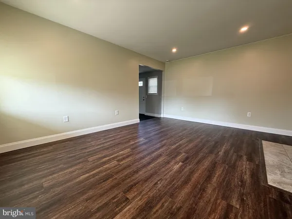 an empty room with wooden floor and natural light