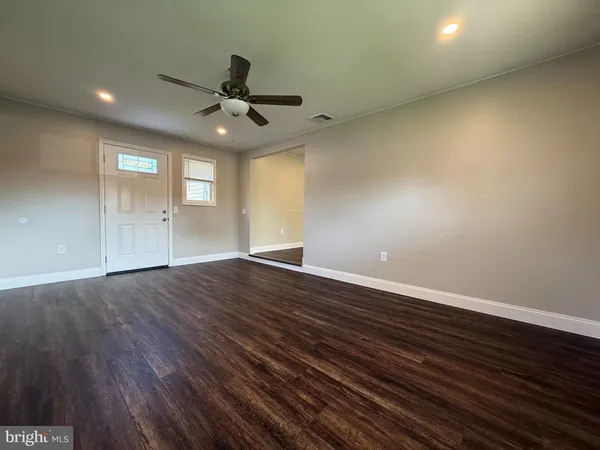 an empty room with wooden floor a ceiling fan and windows