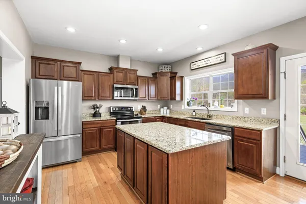 a kitchen with stainless steel appliances granite countertop a sink stove refrigerator and cabinets